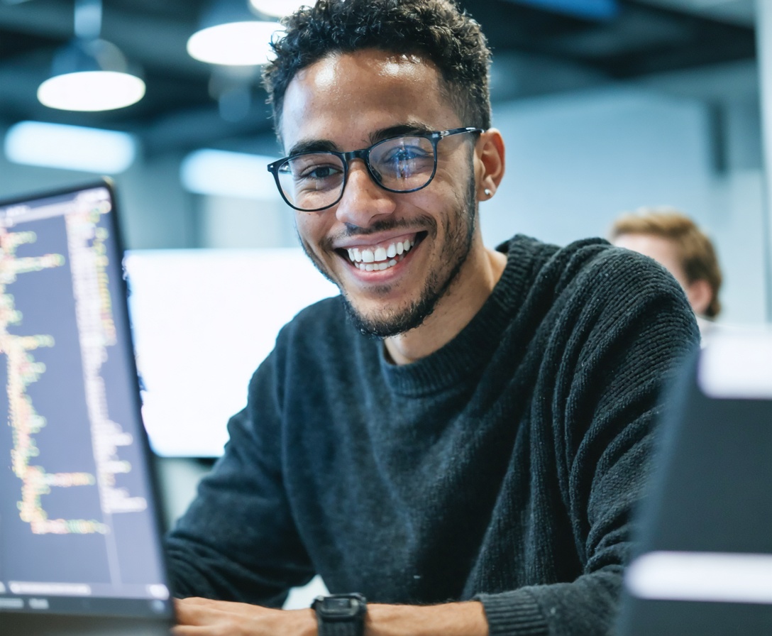 Ein junger Softwareentwickler arbeitet konzentriert an seinem Laptop in einem modernen Büro